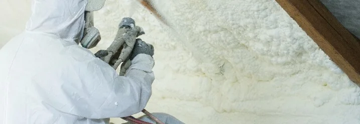 Person dämmt Dach mit Sprühgerät